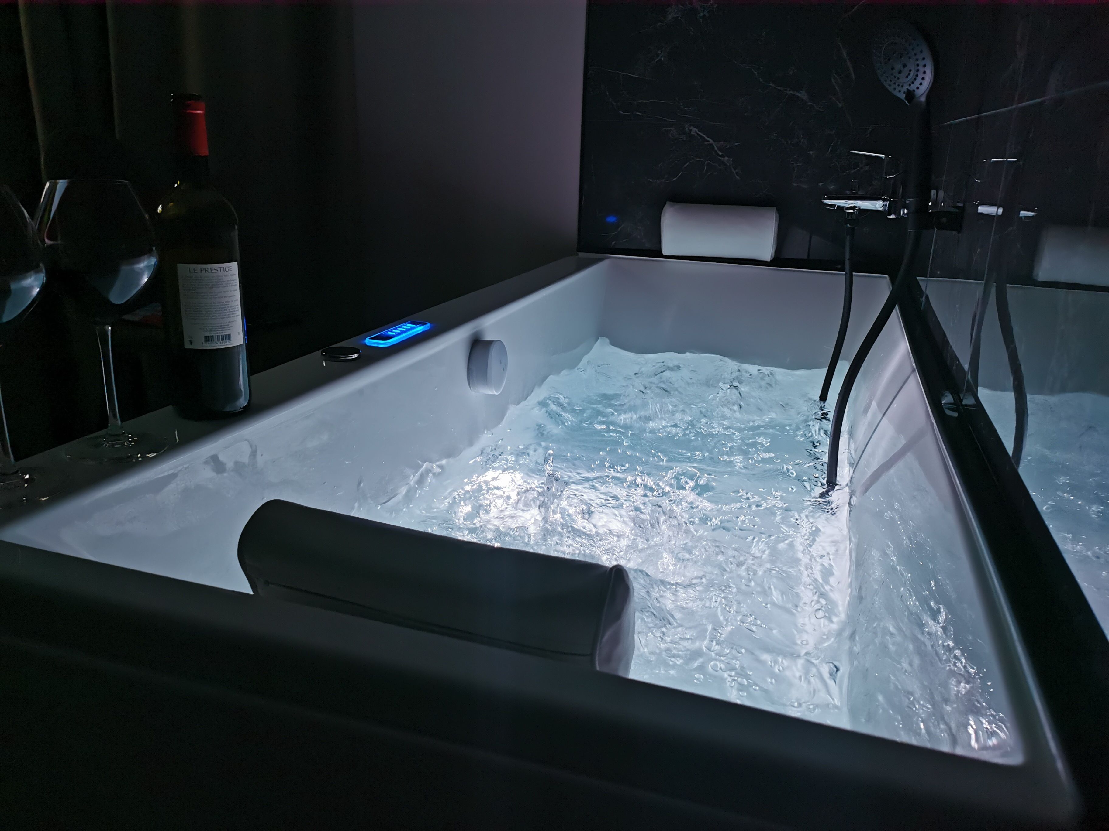 A modern bathroom with a bathtub, a wine bottle, and a wine glass.