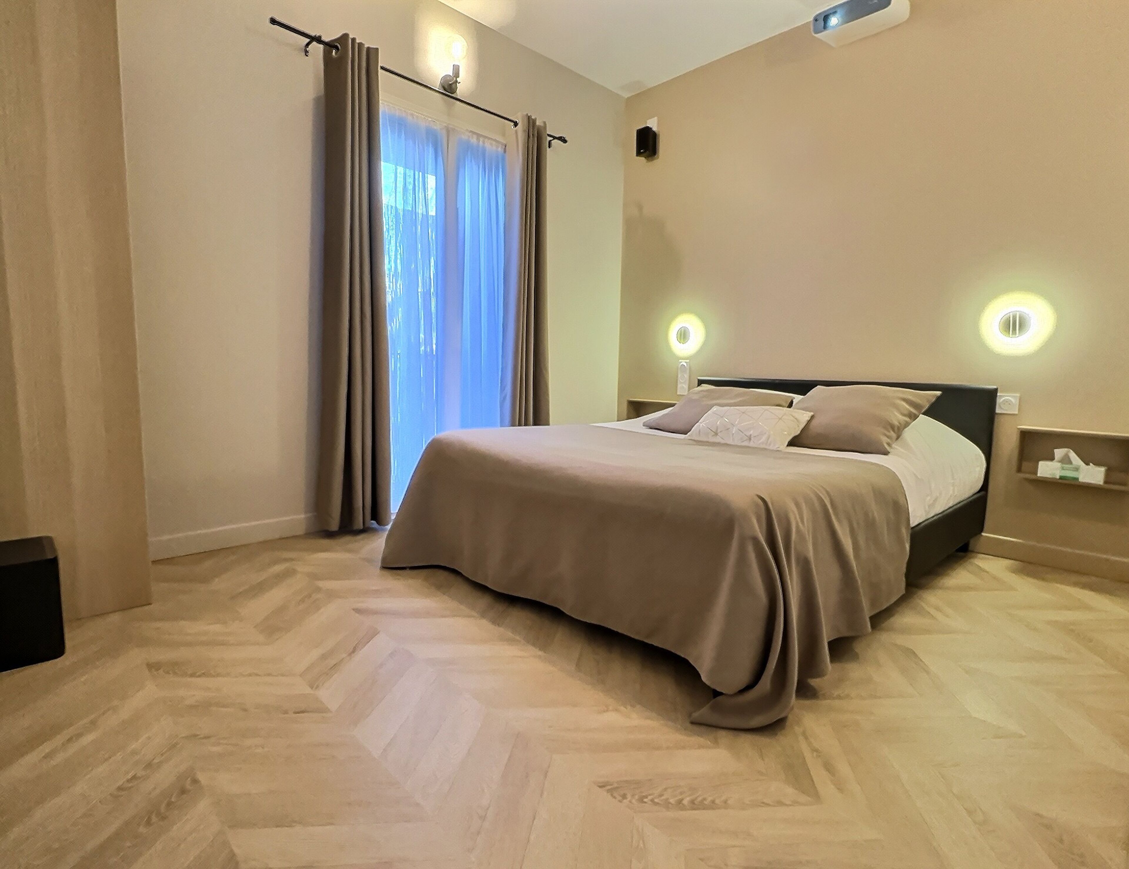 A neatly arranged bedroom with a bed, curtains, and a nightstand with a lamp.