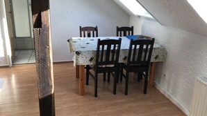 A dining area with a table and chairs, a sloped ceiling, and a view of the adjacent room.