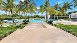 A pool area with a clear view of the pool, surrounded by palm trees and a well-maintained lawn. - Family-Friendly Ocean View Apto in Playa Blanca (Coclé)
