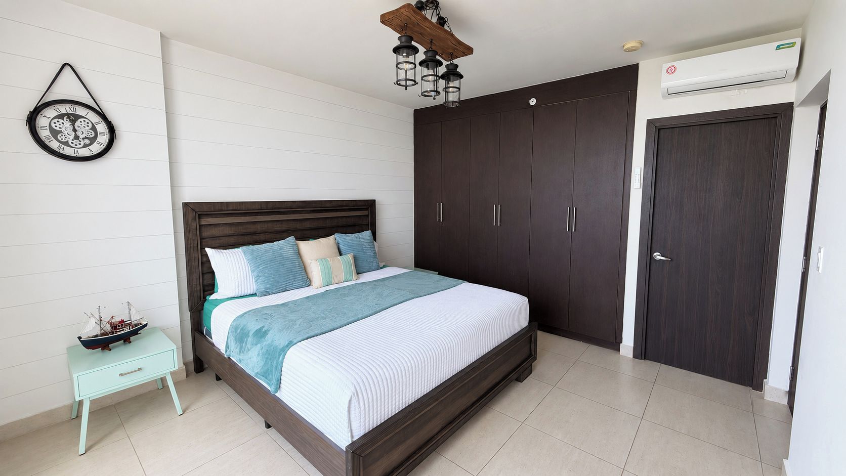 Een slaapkamer met een bed, nachtkastje, kledingkast en een airconditioning.