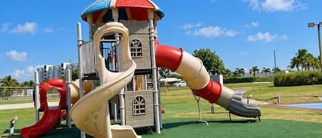 A playground with a slide, climbing structures, and a small tower.