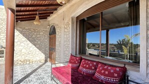 Uma área de estar ao ar livre aconchegante, com ladrilhos estampados, teto de madeira e vista para a paisagem.