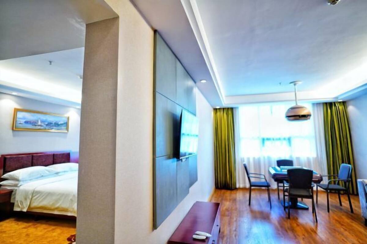 A hotel room with a bed, a desk, a chair, a television, and a window with curtains.