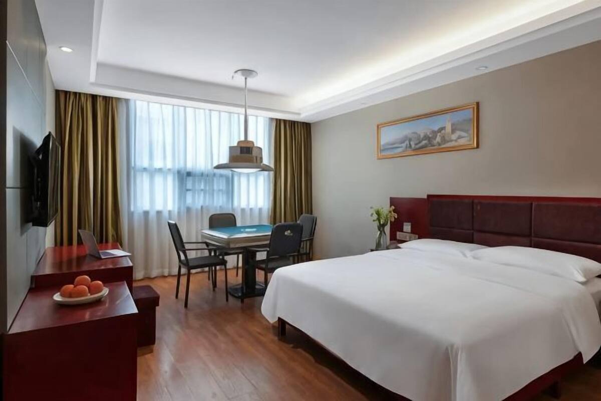 A hotel room with a bed, desk, chair, and a TV.
