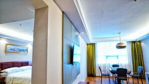 A hotel room with a bed, a desk, a chair, a TV mounted on the wall, and a window with curtains. - Vienna Classic Hotel (Tongren Jiangkou) (Jiangkou)