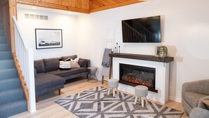 Una sala de estar moderna con chimenea, un sofá, un televisor y una escalera.