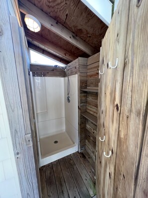 A wooden cabin with a shower area featuring a white bathtub and a showerhead. - Colorful Canal-Front Beach House, Beautiful Water Views, & Short Walk to Beach (Bethany Beach)