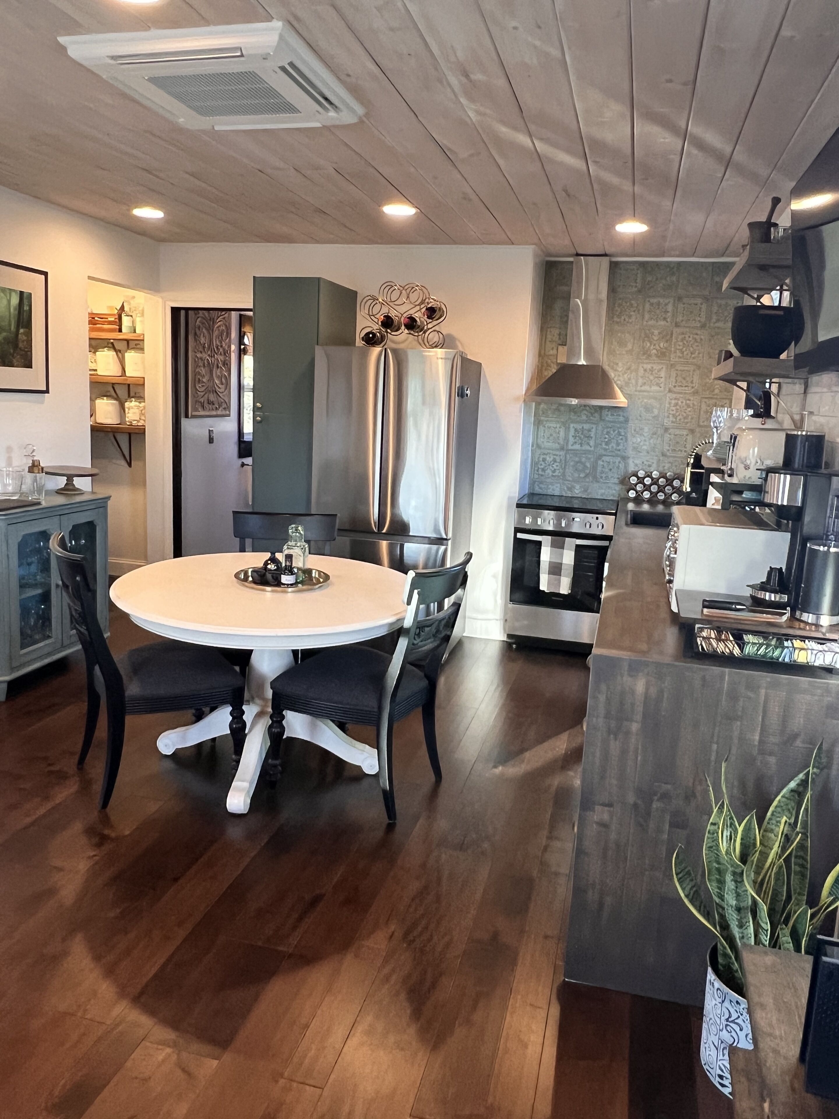 A modern kitchen with a central island, stainless steel appliances, and a dining area with a round table and chairs.