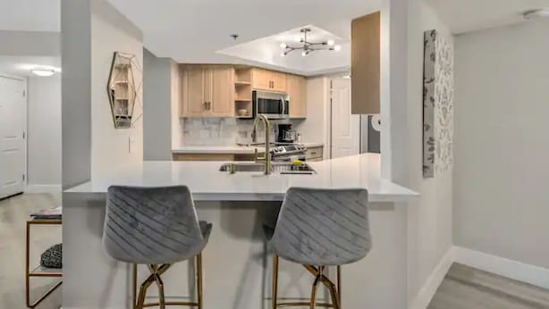 A modern kitchen with white cabinetry, a central island, and two bar stools.