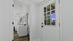 Un interior limpio y luminoso, con piso de madera, una zona de cocina con electrodomésticos y un ventanal con vistas a la vegetación.