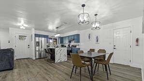 Una cocina moderna con armarios azules, una isla de mármol y un comedor con mesa y sillas.