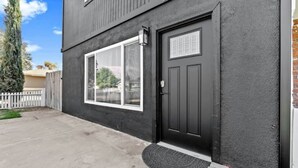 A two-story building with a dark exterior, a large window, and a black door with a small window above it.