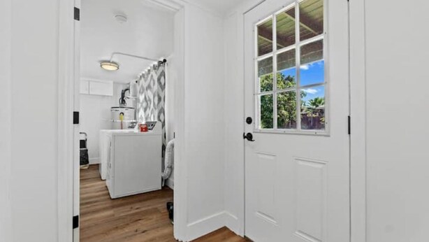 A narrow hallway with a white door leading to a room with a window. A ceiling light is visible in the hallway.
