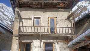 A rustic stone building with a wooden balcony, multiple windows, and a snow-covered ground. - Renovated sheepfold near the slopes ideal for 2 families (CREVOUX)