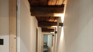 A narrow hallway with wooden flooring and exposed wooden beams on the ceiling. - Renovated sheepfold near the slopes ideal for 2 families (CREVOUX)