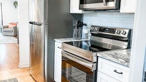 Eine moderne Küche mit Edelstahlgeräten, weißen Schränken und einem gemusterten Teppich.