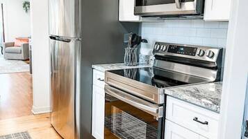 A modern kitchen with stainless steel appliances, white cabinetry, and a patterned rug.