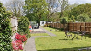 A backyard with a patio area, a wooden fence, and a variety of plants. - Waterfalls House - property akin Waterfall Country (Pontneddfechan)