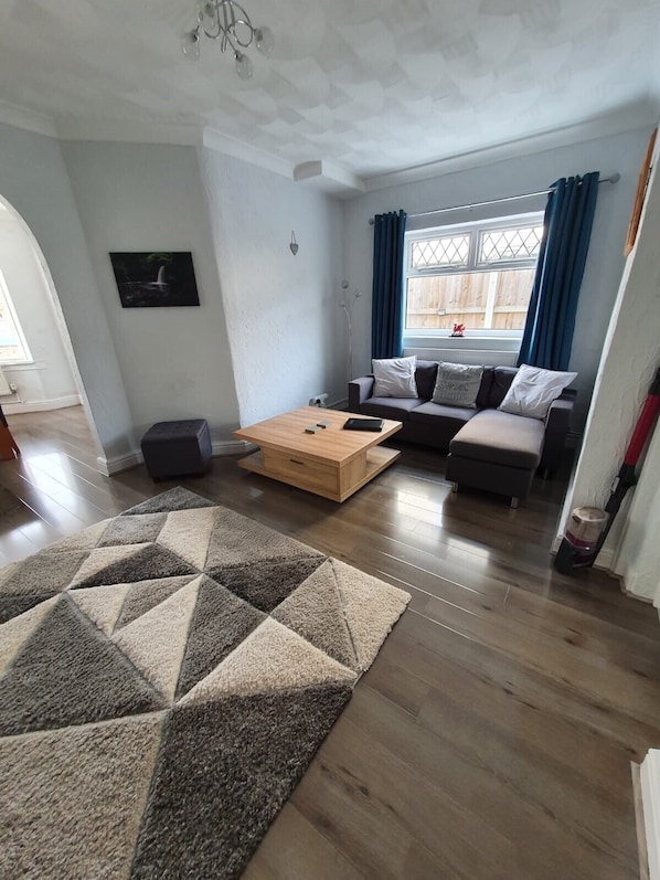 A modern living room with a wooden coffee table, a sofa, and a patterned rug.