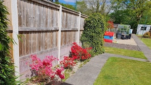 A garden with a wooden fence, a pathway, and a small outdoor seating area with chairs and a table. - Waterfalls House - property akin Waterfall Country (Pontneddfechan)