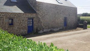 A stone building with two blue doors and a small window.