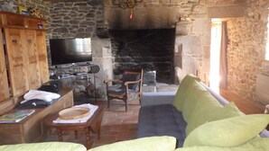 A cozy living room with a stone fireplace, a television, wooden furniture, and a comfortable sofa.