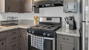 A modern kitchen with stainless steel appliances, a granite countertop, and wooden flooring. - The Cozy Rustic Sequoia Wi-Fi & 2 Garage (Tulare)