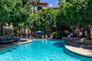 A swimming pool surrounded by lounge chairs and umbrellas, with trees and a building in the background. - Super Host with great reviews! Fantastic Location- Biltmore Luxury Condo (Phoenix)