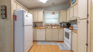 A kitchen with white cabinets, a refrigerator, a dishwasher, a sink, a stove, and a window with blinds. - Sunshine and Relax! (Zephyr Hill)