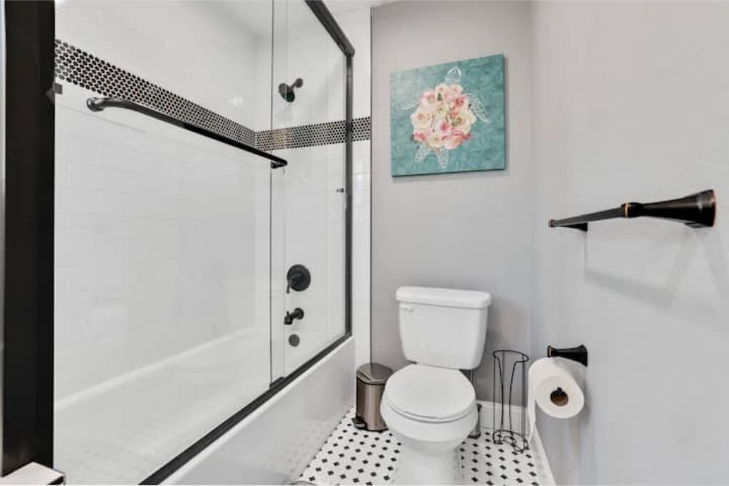 A bathroom with a shower, toilet, and a painting on the wall.