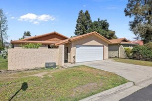 Stucco and stone house with a tiled roof and a garage.