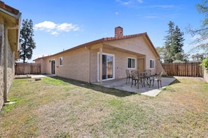 A single-story house with a patio area, a covered outdoor seating area, and a wooden fence.