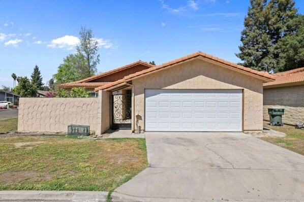 A single-story house with a garage, a small front yard, and a clear sky.