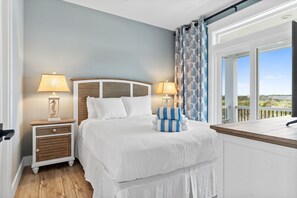 Een slaapkamer met een bed, twee nachtkastjes, een raam met gordijnen en uitzicht op de omgeving.