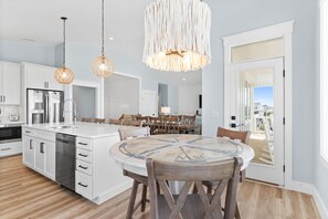 A modern kitchen with white cabinetry, a central island, and a dining area with a round table.
