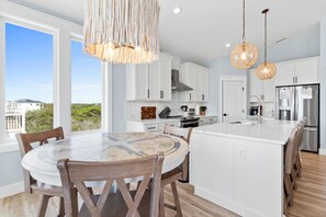 A modern kitchen with white cabinetry, a large island, and pendant lighting.