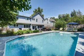 A residential swimming pool with a house in the background.
