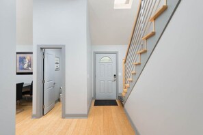 A hallway with a wooden floor, a grey door, and a staircase with wooden steps. - Luxury in Lenexa w/heated pool (Lenexa)