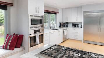 A modern kitchen with white cabinets, stainless steel appliances, and a gas stove.