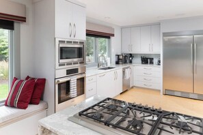 Una cucina moderna con mobili bianchi, elettrodomestici in acciaio inossidabile e piano cottura a gas.