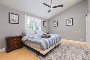 Un dormitorio con cama, cómoda, ventilador de techo y cuadros en las paredes.