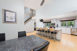 A modern kitchen with a central island, bar stools, and a staircase leading to an upper level. - Luxury in Lenexa w/heated pool (Lenexa)