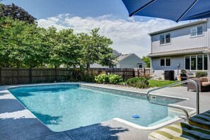A rectangular swimming pool with a metal ladder and a blue umbrella. - Luxury in Lenexa w/heated pool (Lenexa)