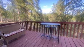 Une terrasse en bois avec un canapé en osier et une petite table.