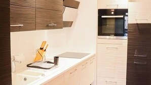 Et moderne køkken med indbygget ovn, vask og bordplade med knivholder.