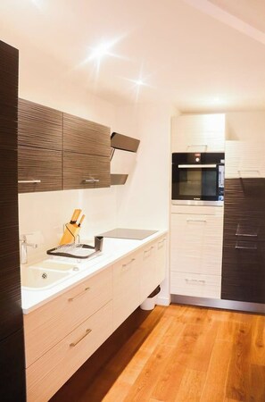 Una cocina moderna con horno empotrado, un lavamanos y una encimera con un soporte para cuchillos.