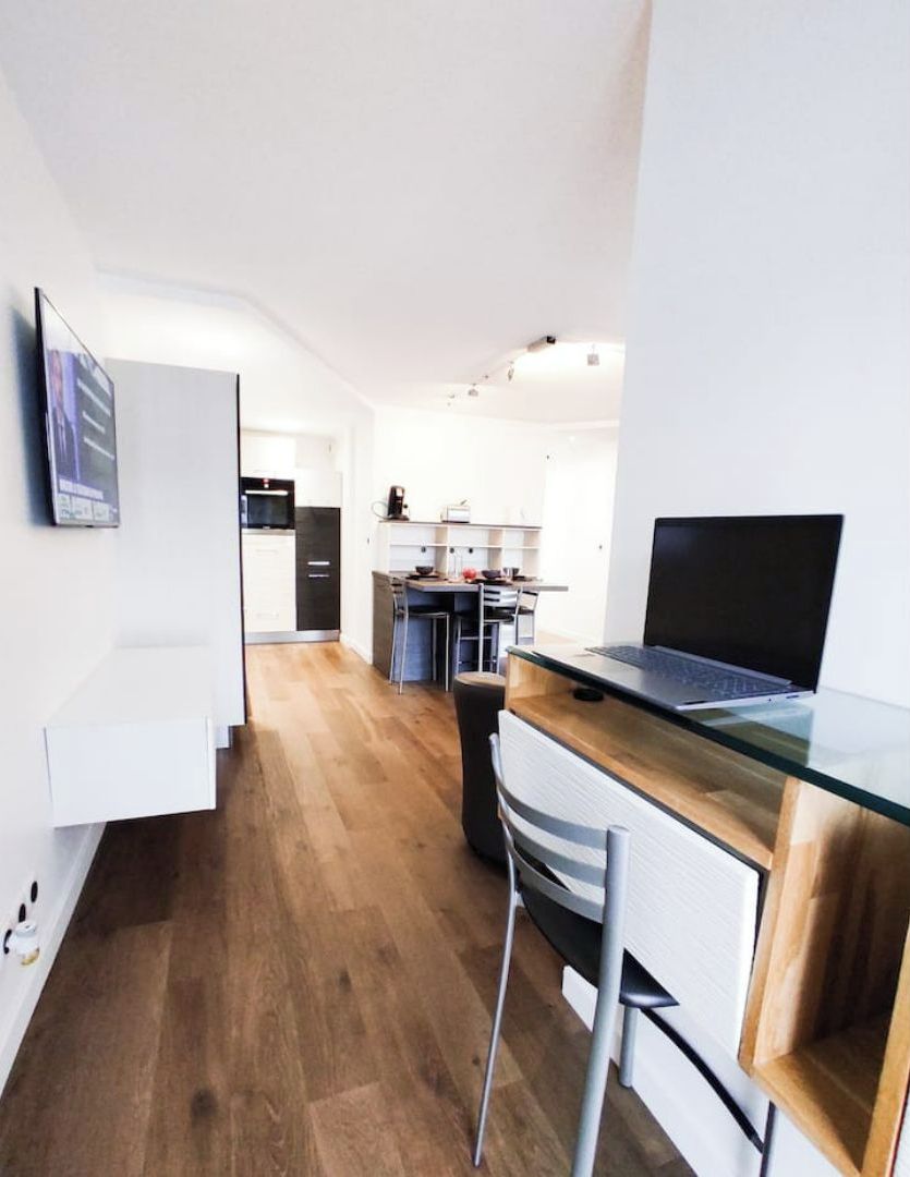 Una cocina moderna con encimera de madera, un ordenador portátil y un comedor con una silla.