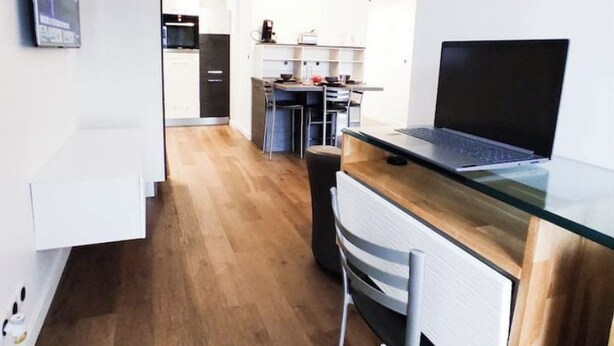 Et moderne køkken med en træbordplade, en bærbar computer og en spiseplads med en stol.