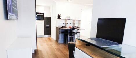 Una cocina moderna con encimera de madera, un ordenador portátil y un comedor con una silla.